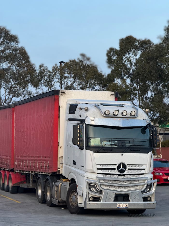 Home White and red semi truck parked outdoors at logistics hub, ready for transportation.