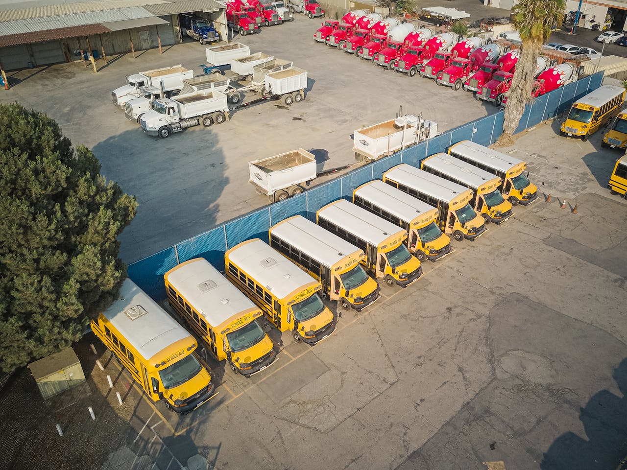 Home Aerial view of school buses and trucks parked in an industrial lot.